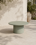Tavolino ARKÉ MANOFATTI in finitura verde salvia ambientato su una terrazza mediterranea con ombre di ulivo