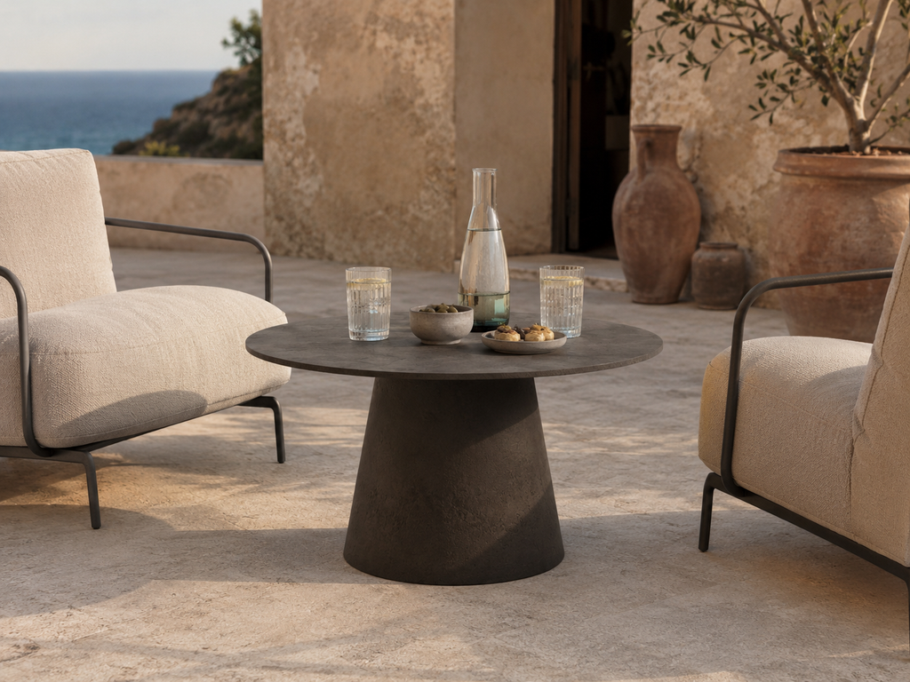 Tavolo basso ORBIS MANOFATTI in finitura tabacco scuro ambientato in una lounge outdoor mediterranea vista mare