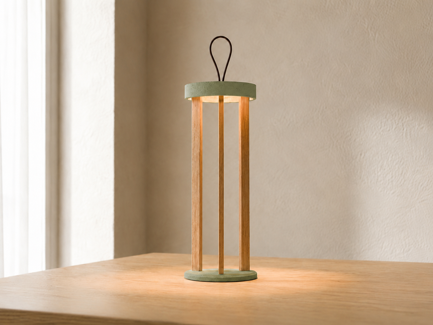 Lampada portatile TIZIA MANOFATTI in finitura verde salvia accesa su tavolo in legno in un interno dai toni caldi